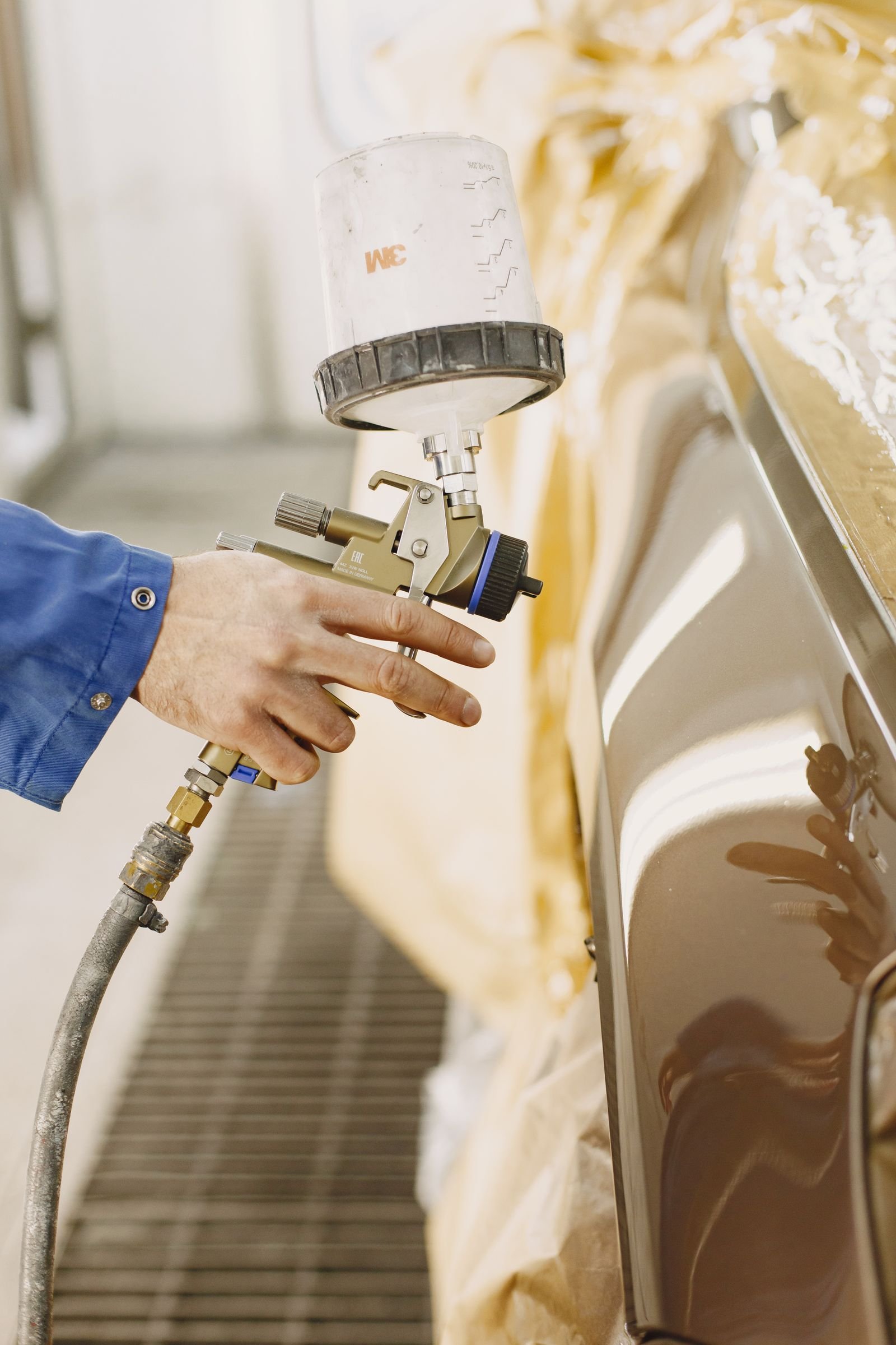 Auto body technician using a paint spray gun in a Florida collision repair shop