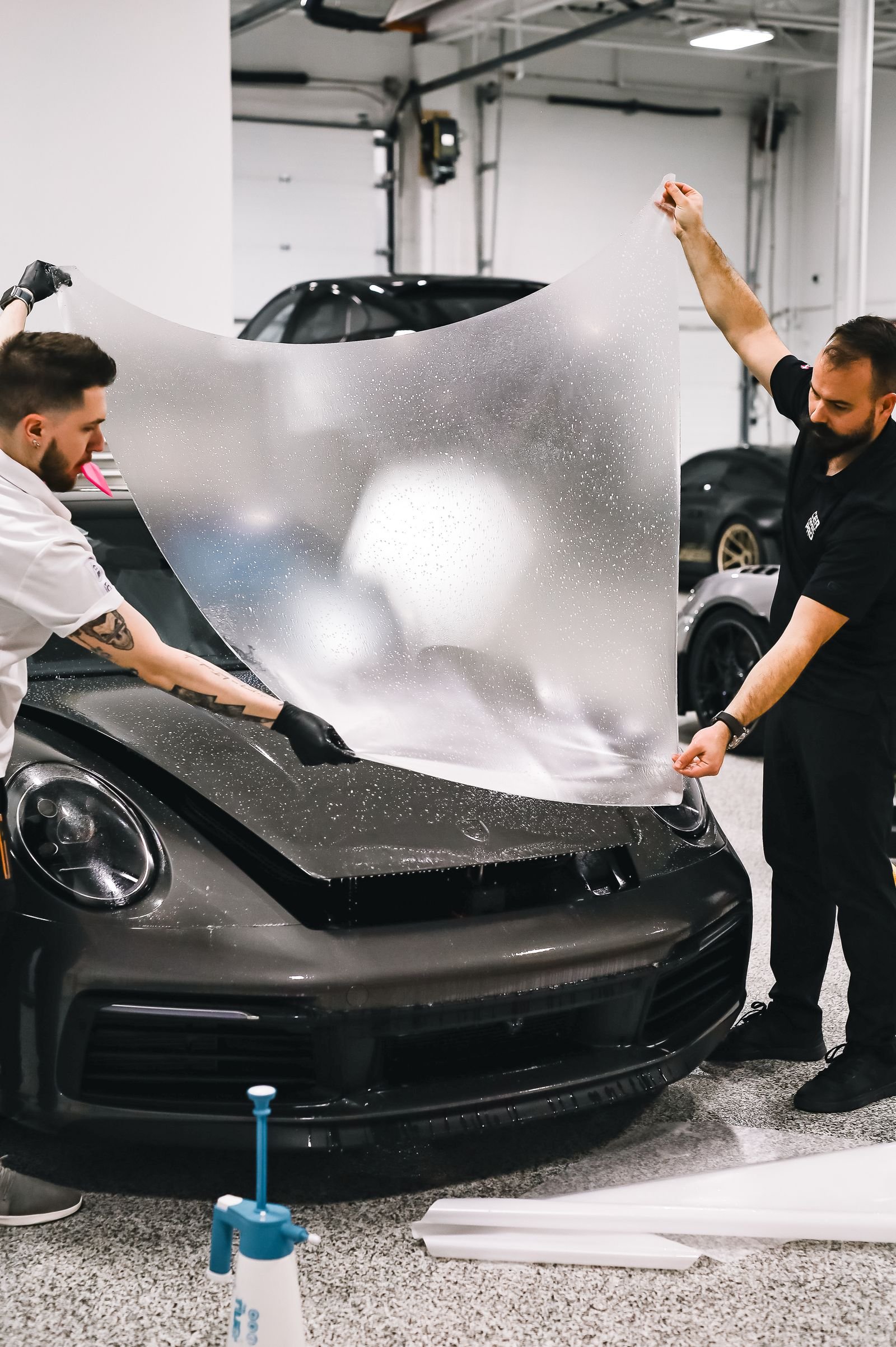 Two PPF installers fitting paint protection film over a car panel in Florida