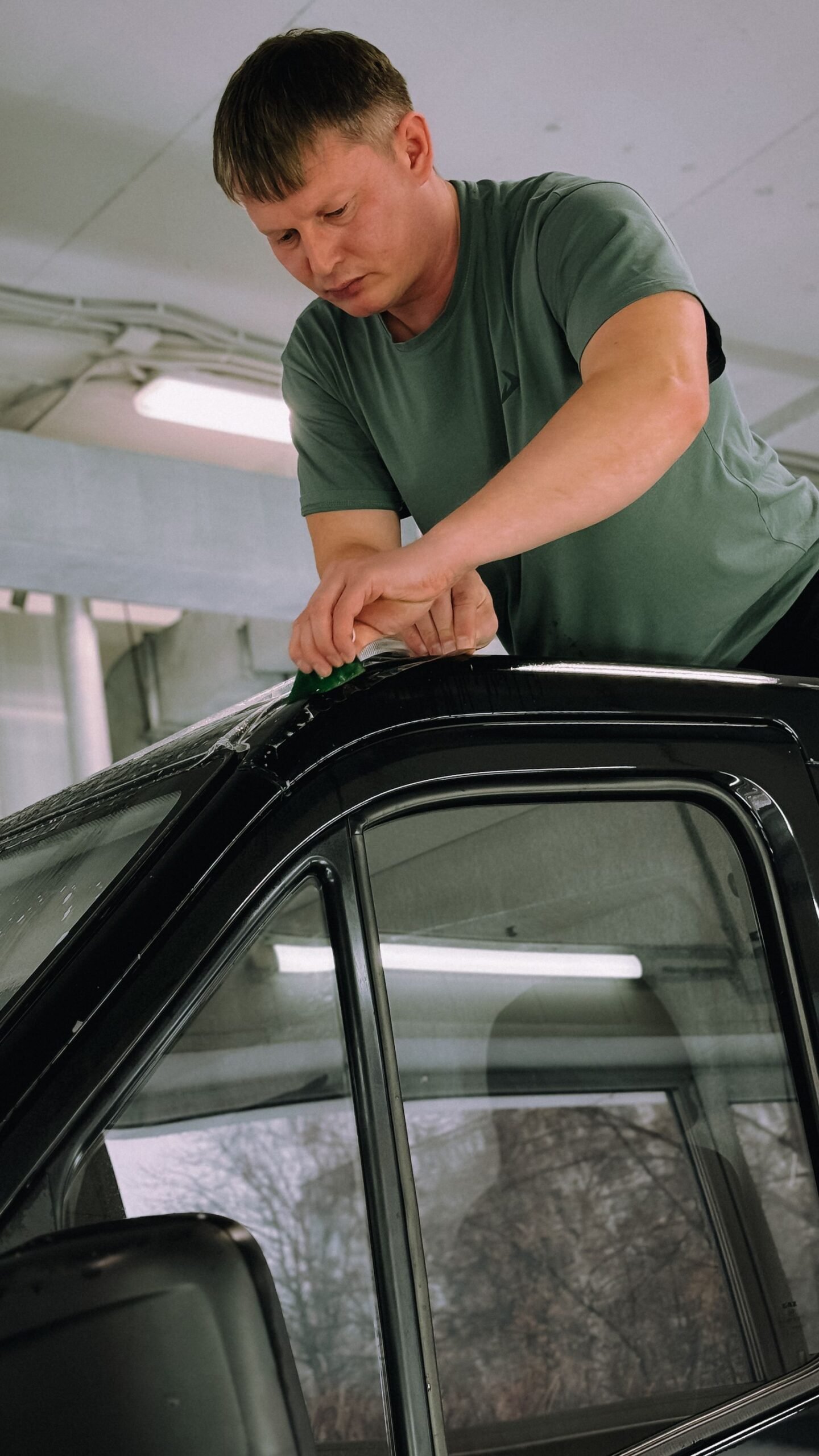 Technician installing window tint film on a car in a Florida shop