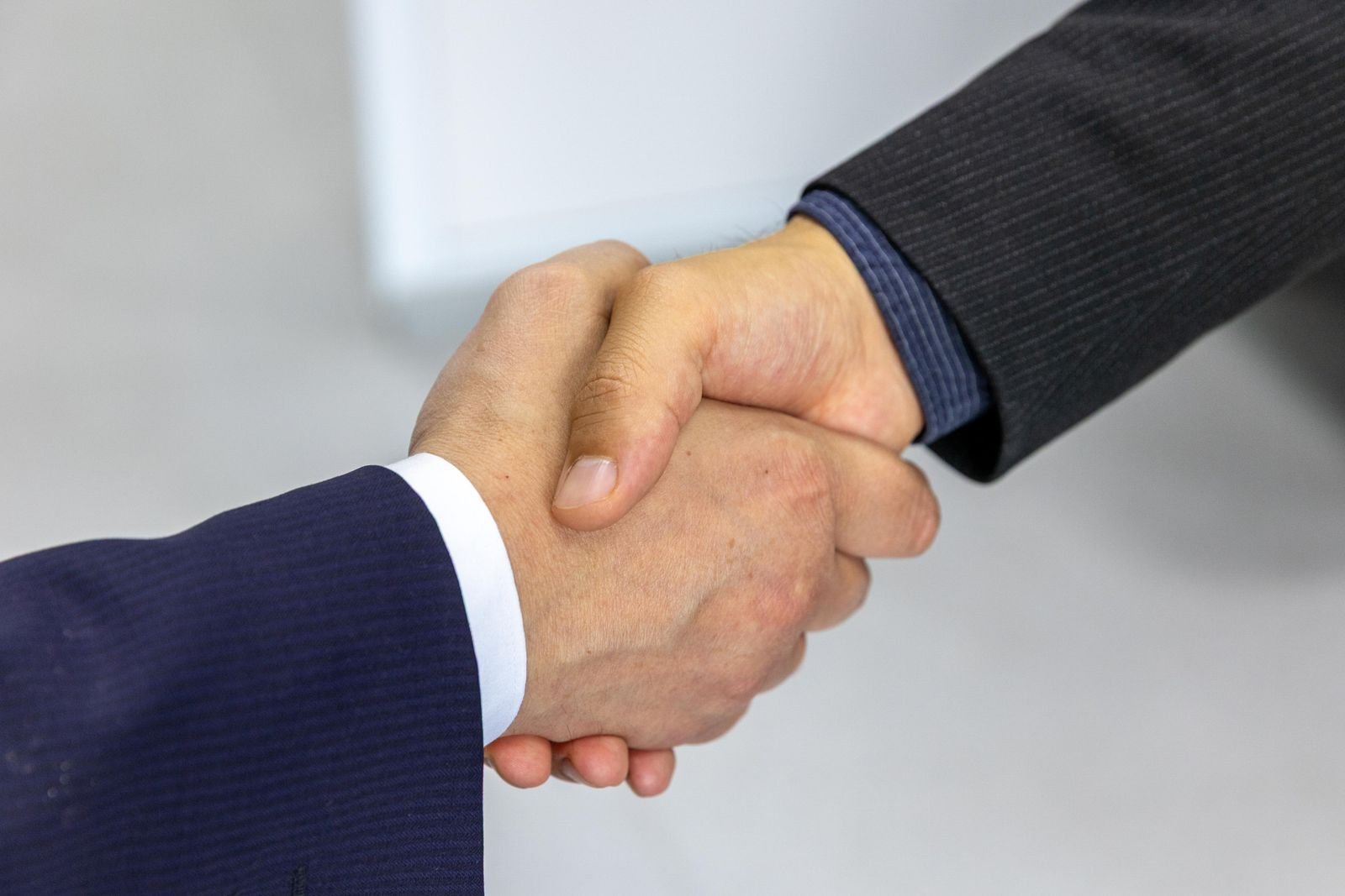 Vehicle wrap shop owner shaking hands to close a fleet contract
