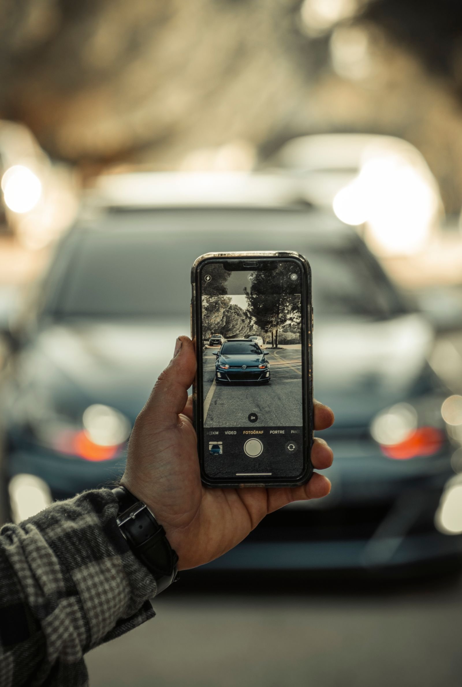 Person filming a car detail transformation on a smartphone for social media