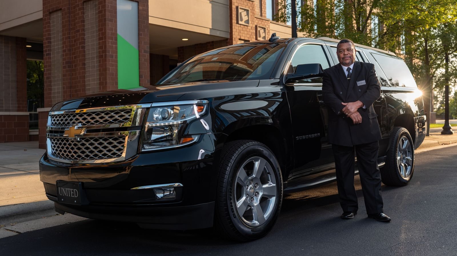Professional chauffeur standing beside a luxury SUV for a Florida corporate account