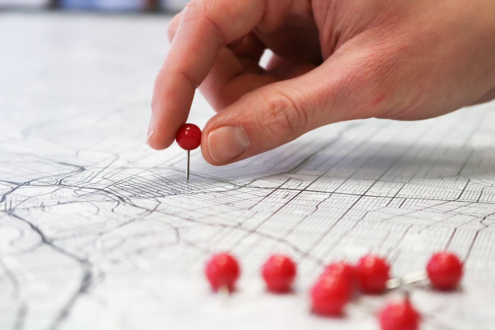 Hand placing a pin on a map to mark a Jacksonville Florida auto body shop service area