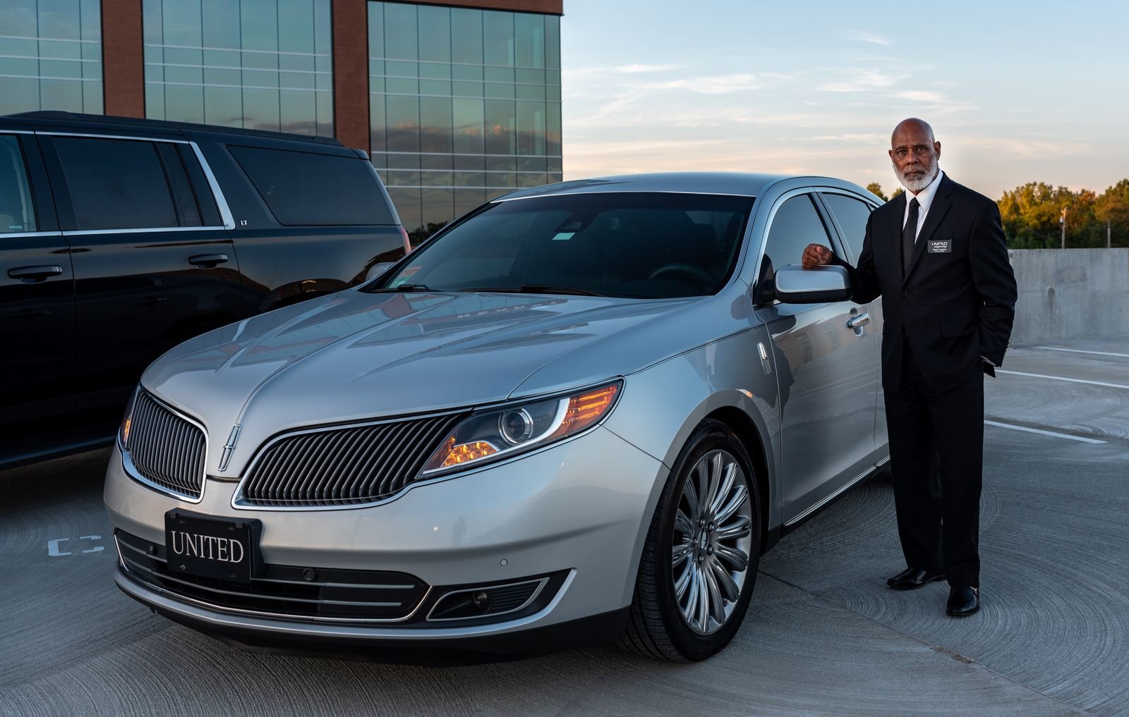 Professional chauffeur standing beside a luxury car, representing chauffeur marketing in Miami Florida